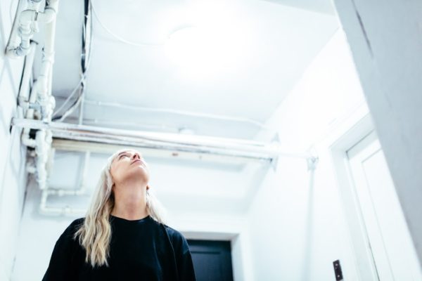 woman staring at pipes on ceiling - premier heating and cooling